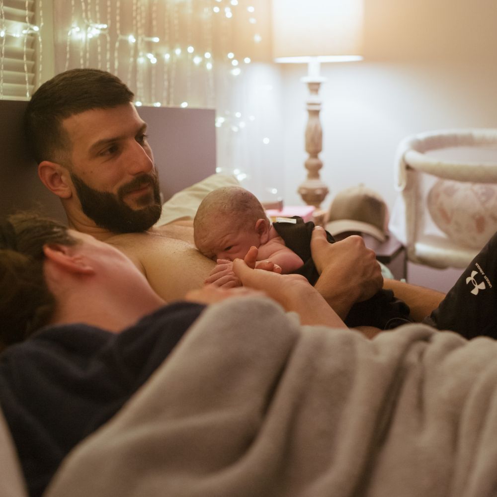 couple in bed with newborn baby after homebirth